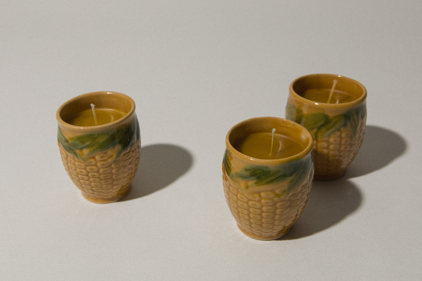 Set of three beeswax CANDLE in corn-motif faience holder
