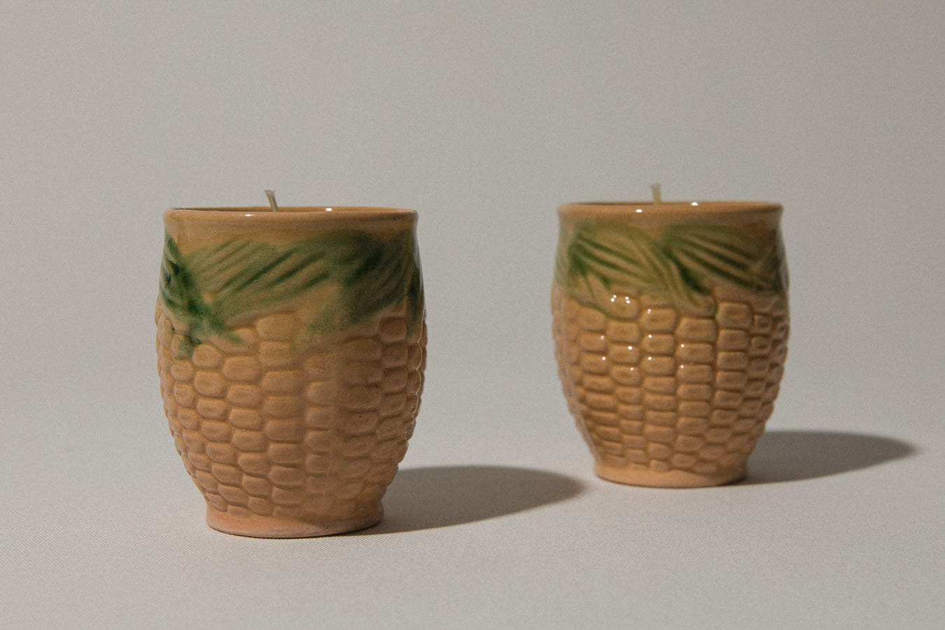 Set of two beeswax CANDLE in corn-motif faience holder
