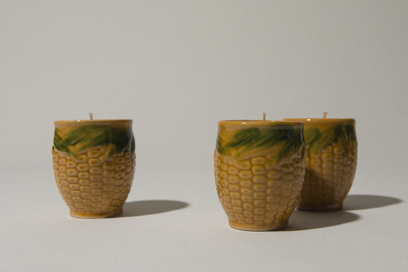 Set of three beeswax CANDLE in corn-motif faience holder