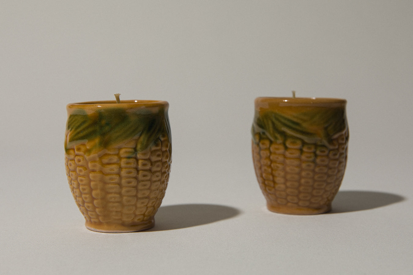 Set of two beeswax CANDLE in corn-motif faience holder