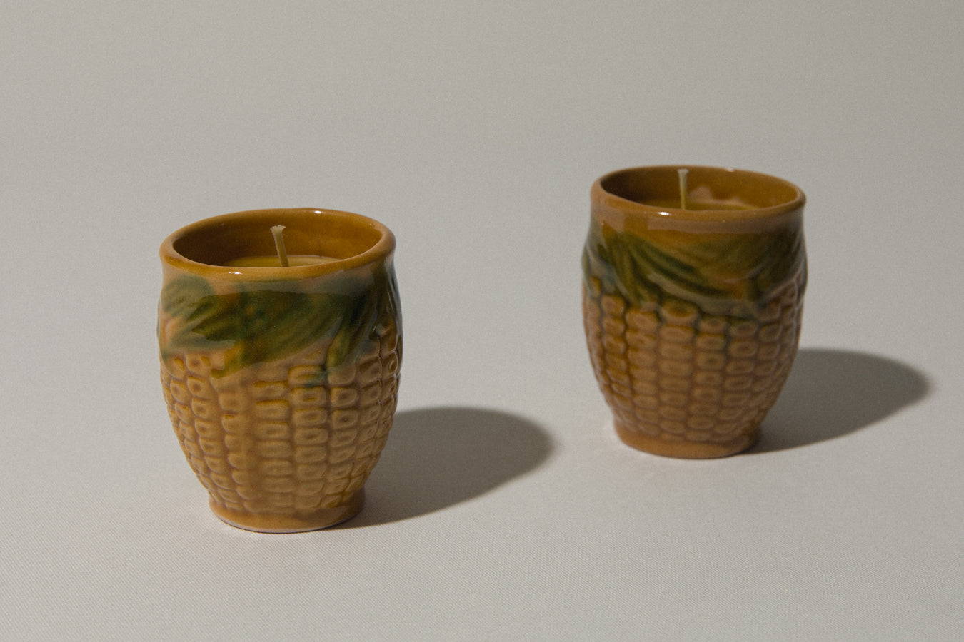 Set of two beeswax CANDLE in corn-motif faience holder