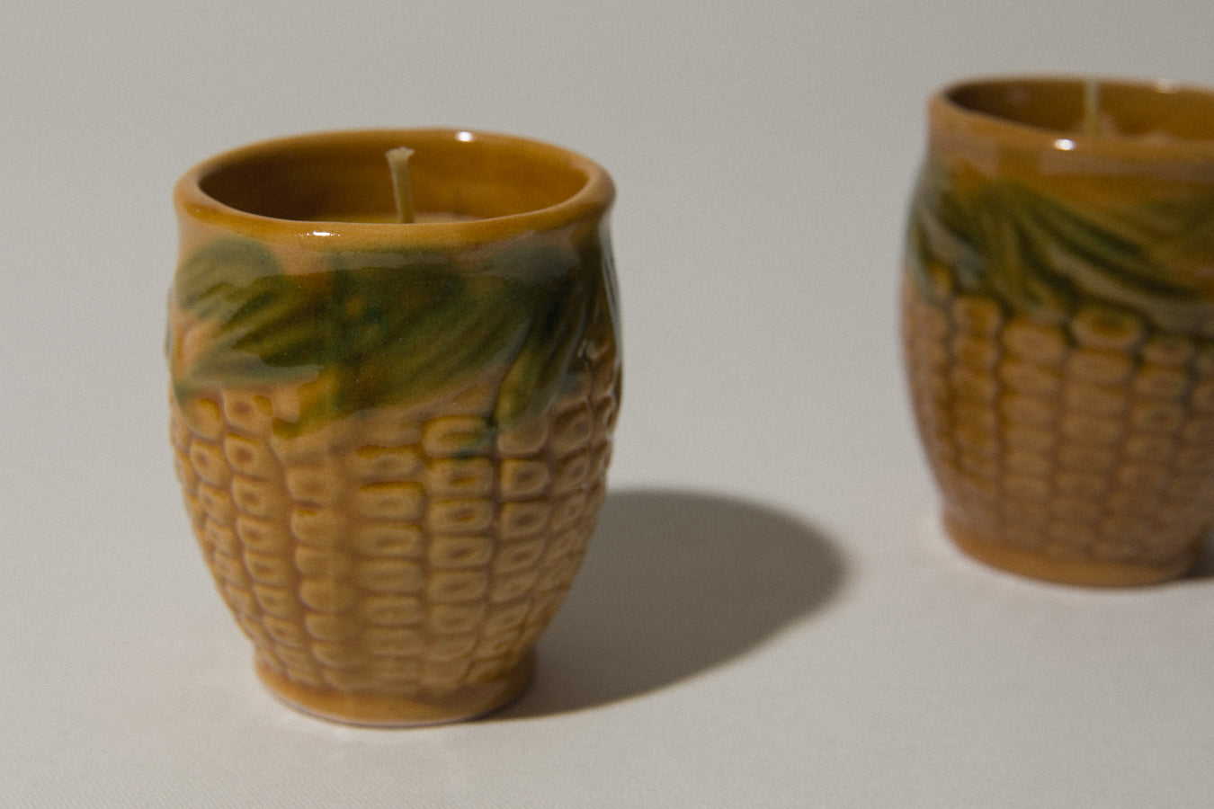 Set of two beeswax CANDLE in corn-motif faience holder