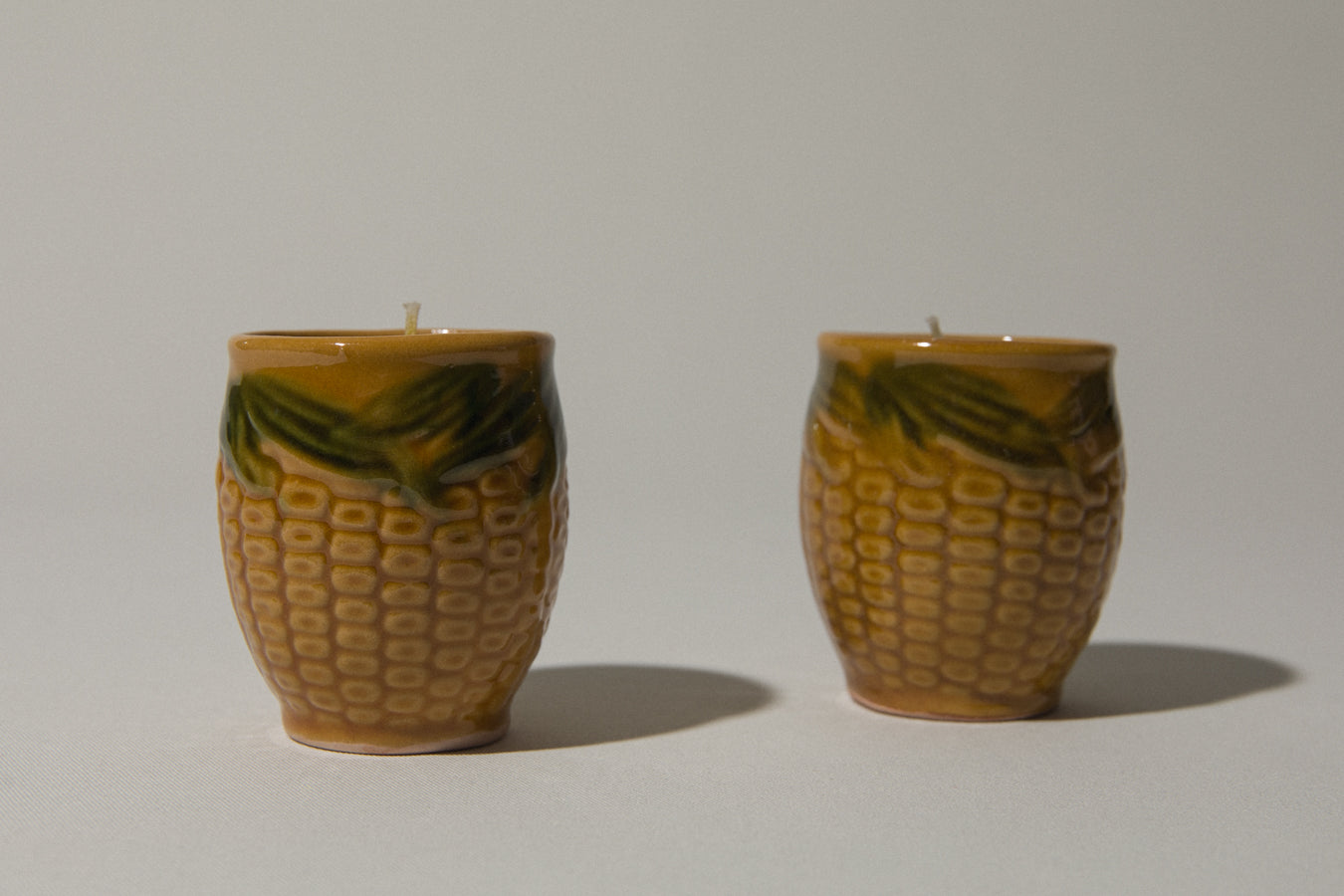 Set of two beeswax CANDLE in corn-motif faience holder