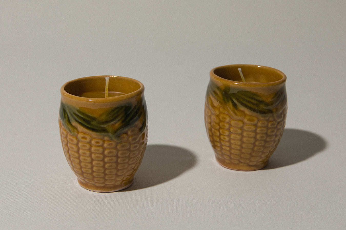 Set of two beeswax CANDLE in corn-motif faience holder