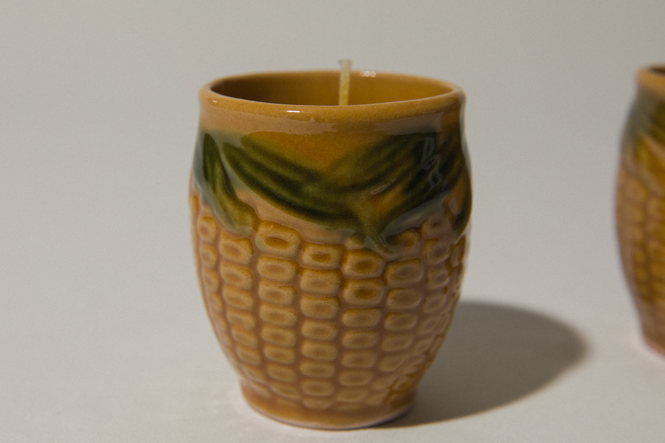 Set of two beeswax CANDLE in corn-motif faience holder