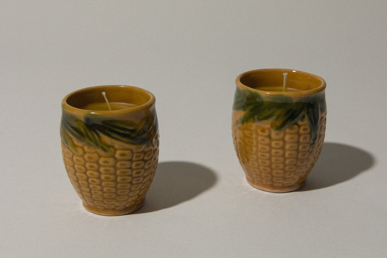 Set of two beeswax CANDLE in corn-motif faience holder
