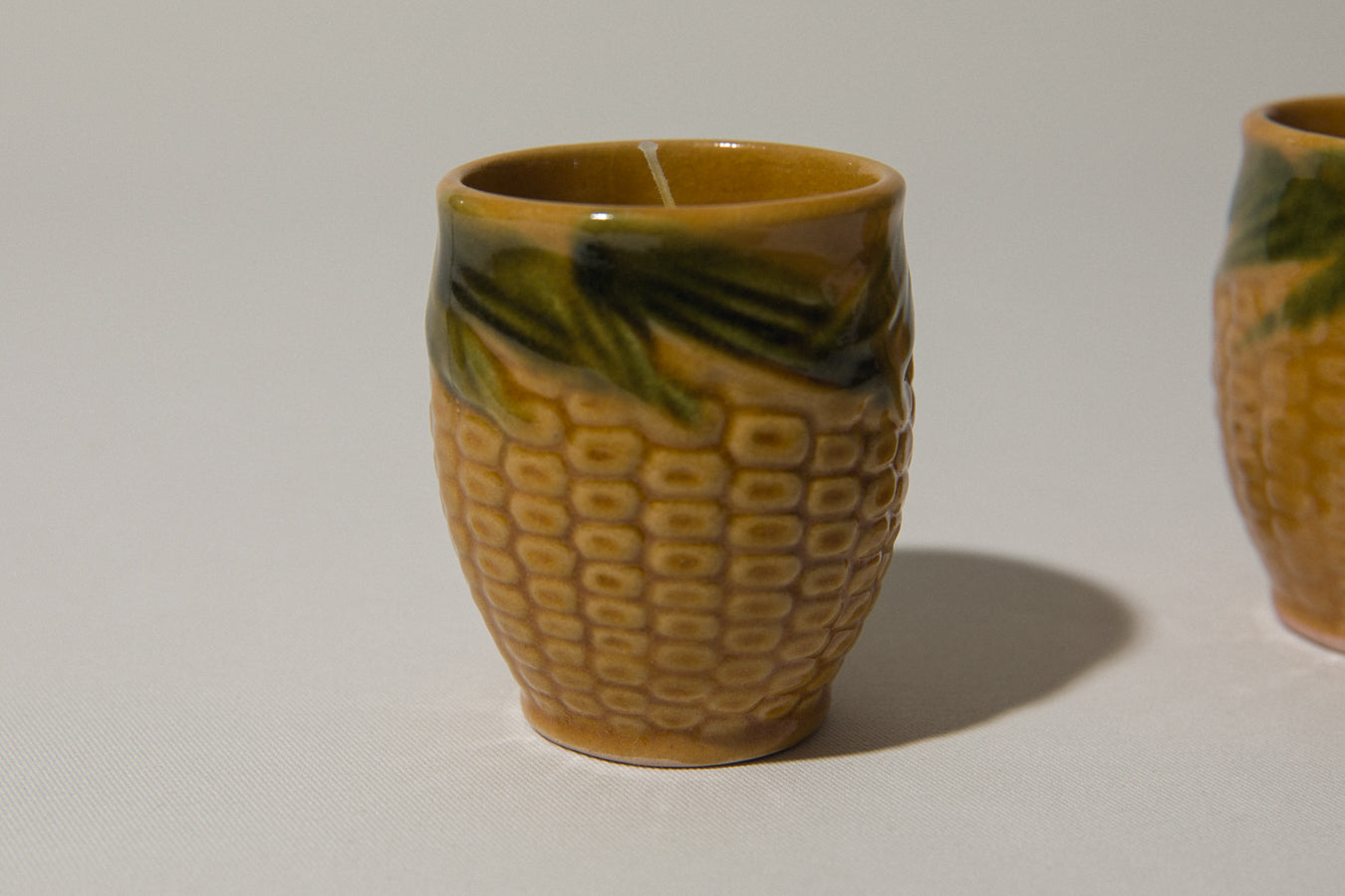 Set of two beeswax CANDLE in corn-motif faience holder