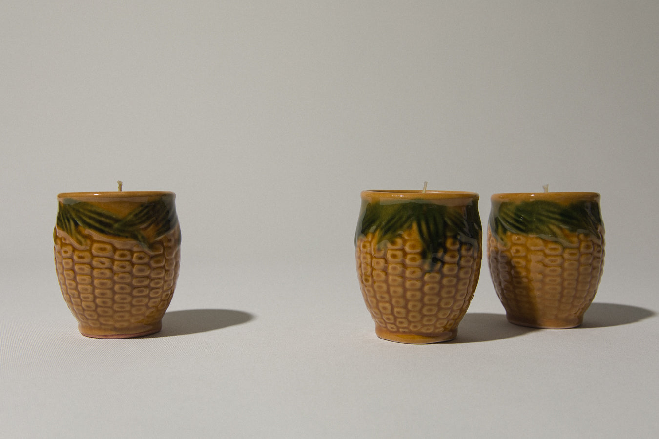 Set of three beeswax CANDLE in corn-motif faience holder