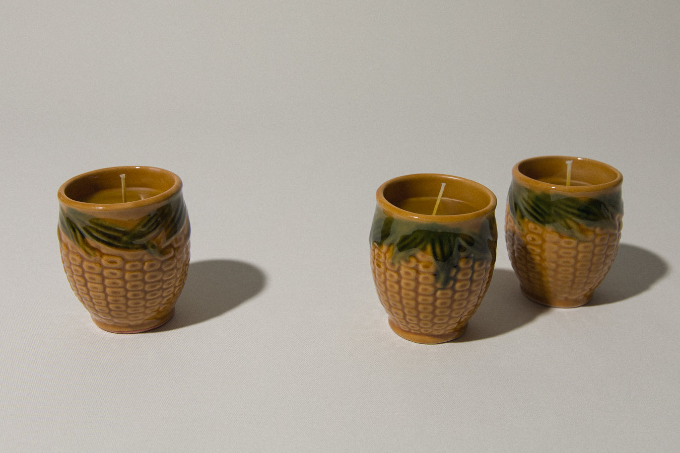 Set of three beeswax CANDLE in corn-motif faience holder